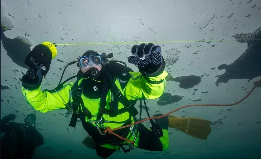 Diver in a yellow Weldman suit underwater.